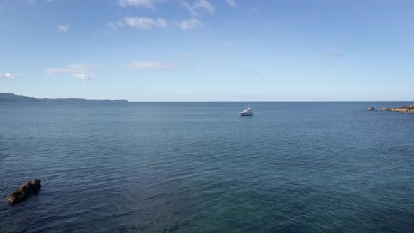 Distant View From Tawharanui Peninsula Of A Luxury Yacht In The Middle Of The Sea In New Zealand. wi