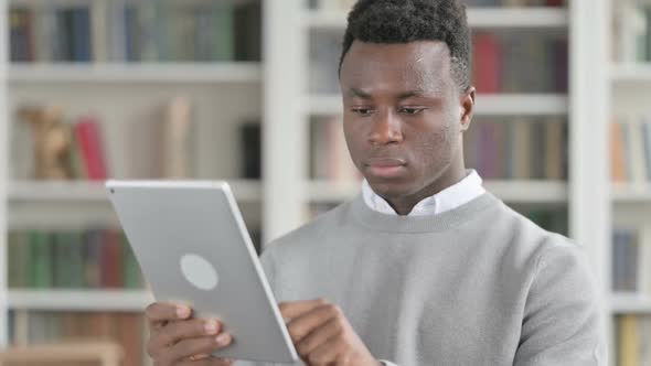 Portrait of Attractive African Man Using Tablet in Library