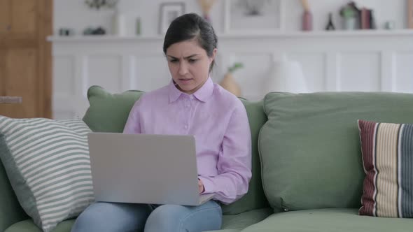 Indian Woman with Laptop Reacting to Loss on Sofa