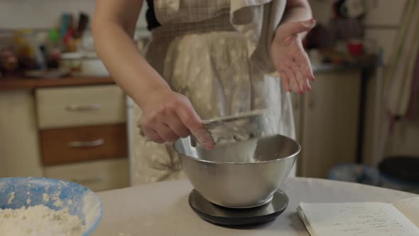 Woman Sifting Flour with a Sifter in the Kitchen
