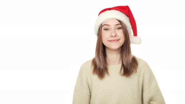 Portrait of Beautiful Woman in Santa Claus Red Hat Demonstrating Product or Service During New Year