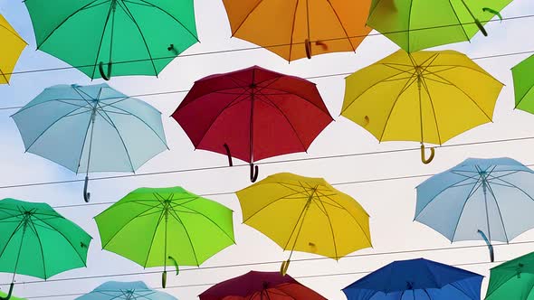 Flying Umbrellas. Multi Colored Parasol Soar in the Sky. Umbrellas Suspended Above Their Heads