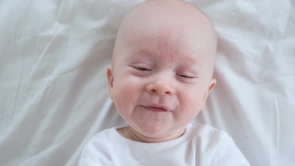 portrait of a cheerful baby in white on the bed