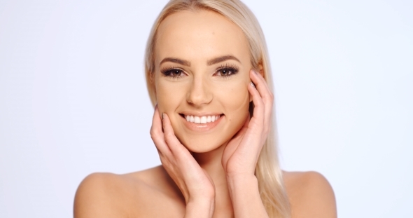 Cheerful Woman Touching Her Face Against White