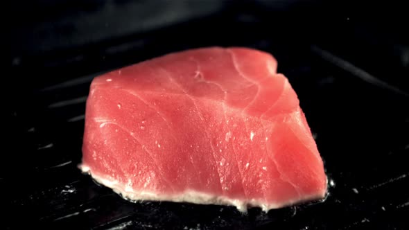 Super Slow Motion Tuna Steak is Fried in a Grill Pan with Splashes of Oil