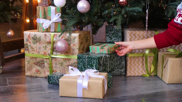 Woman's hand preparing gifts under the Сhristmas tree