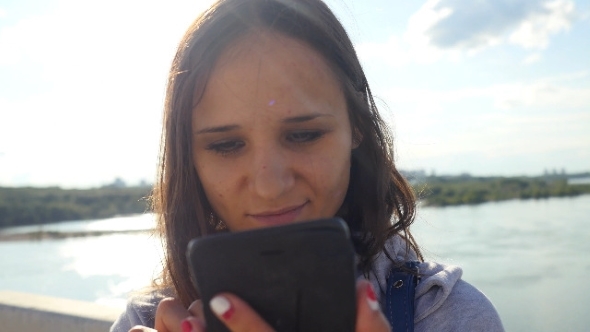 Young Beautiful Woman At Bridge Uses Mobile Phone