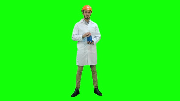 Engineer in Helmet and White Coat Starting Building Demolition on a Green Screen, Chroma Key.