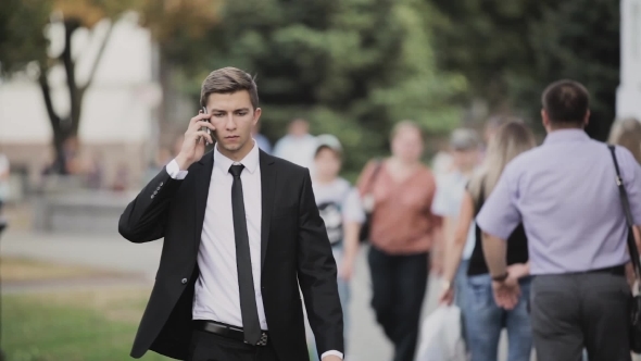 Young Businessman Walking Down The Street, Talking
