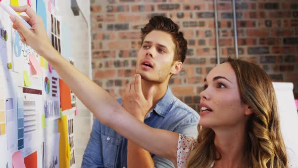 Business executives looking at sticky notes on whiteboard