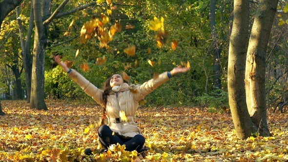 Young Girl Having Fun Throwing Yellow Leaves.