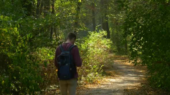 Man In Maroon Shirt With Backpack On His Back