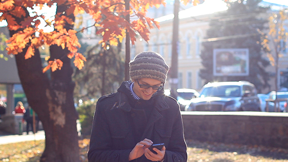 Young Man Using a Phone In The Park alt