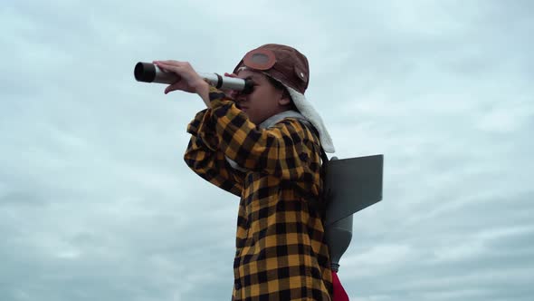 Funny Asian child girl playing with toy rocket and looking through telescope, Kid pl