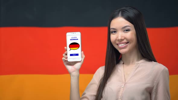 Female Showing Cellphone With Learn German App, Flag on Background, Education