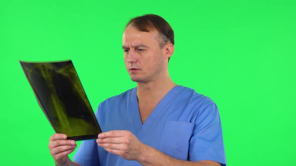 Male Doctor Reviewing X-ray Pointing on Snapshot, Explains and Shakes His Head Negatively Shrugs