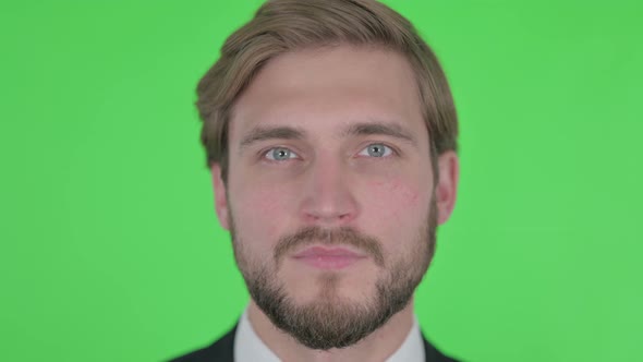 Close Up of Serious Young Businessman on Green Background