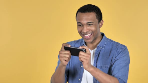 Young African Man Playing Game on Smartphone