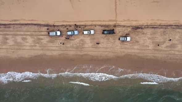 overhead aerial shot of cars on the beach at the edge of the Namib desert with the sea coming in