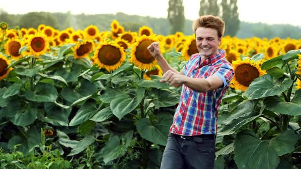 Successful Male-farmer Dancing Fun on Sunflowers Field, Pleased and Positive on Sunset. Farming
