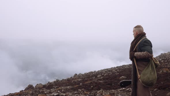 Man In Greatcoat Standing In Misty And Rocky Landscape