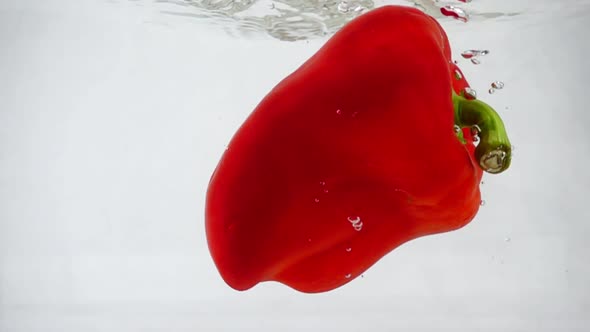 Red Bell Pepper Falls Into Water with Splashes and Bubbles