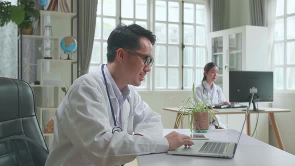 Asian Male Doctor Communicates With Patient By Video Link, Doctor Consults Patient