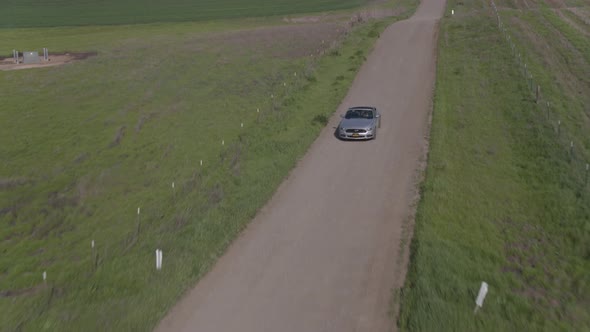 Car Driving On The Dirt Road Among Windmills