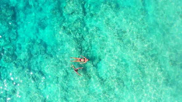 Pretty fun women on photoshoot enjoying life on the beach on clean white sand and blue 4K background