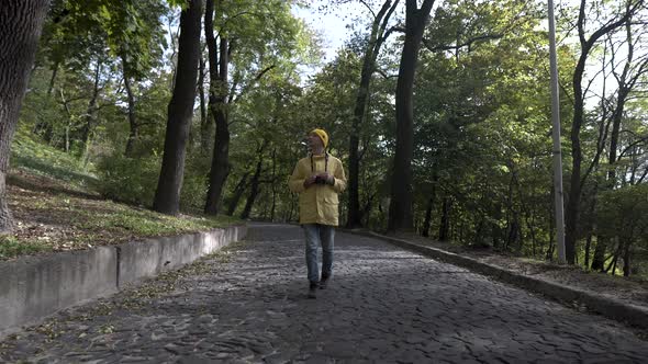 Travel Photographer Takes a Picture in a Park with Trees