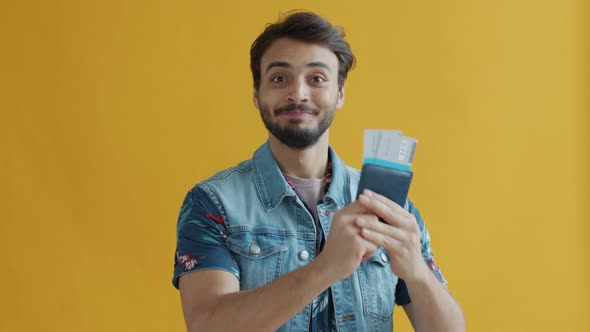 Overjoyed Middle Eastern Man Holding Passport with Plane Ticket Kissing Document Expressing