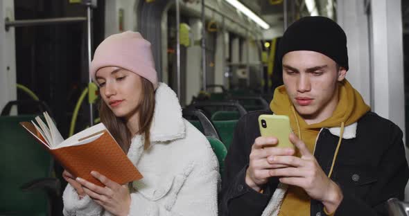 Young Handsome Guy Using His Smartphone While Sitting Near His Girlfriend. Millennial Attractive