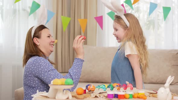 Mother and Sweet Daughter Play with Easter Eggs in Game of Who Will Break