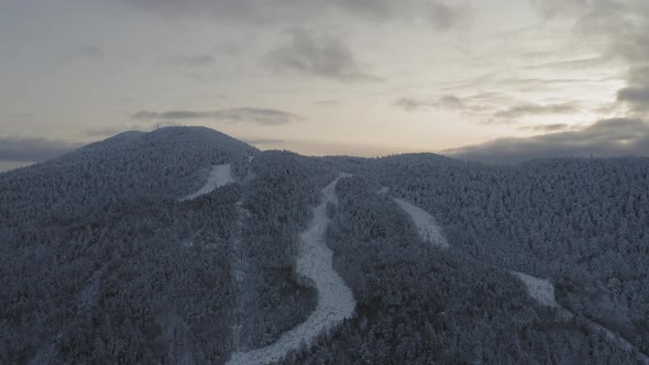 Abandonded ski lift and trails at the peak of a snow covered mountain AERIAL PULL BACK