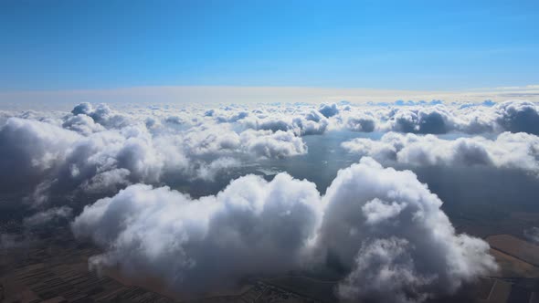 Aerial View From Airplane Window at High Altitude of Earth Covered with Puffy Cumulus Clouds Forming