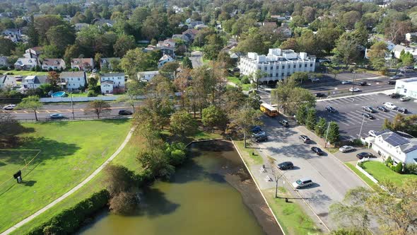 An aerial drone shot over a green pond in a suburban neighborhood on Long Island, NY.  The camera do