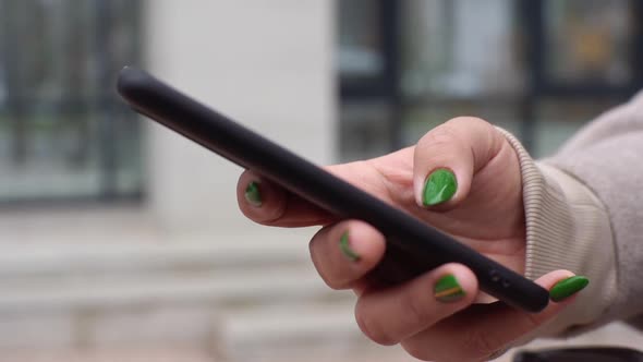 Closeup Hands of Unrecognizable Woman Scrolling Social Media Using Smartphone Standing in City