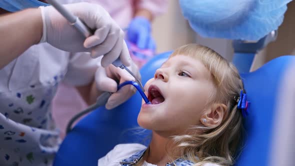 Little child in stomatology chair - close up. Cute blonde girl opened her mouth for teeth check up.