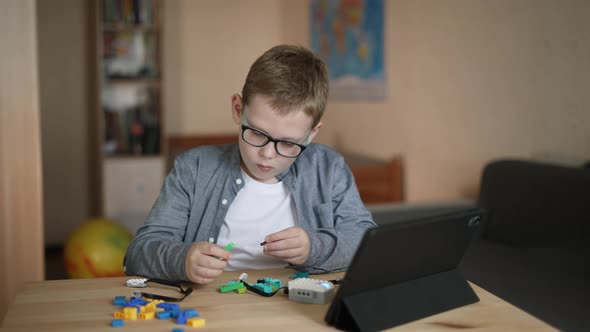 Caucasian Boy with Glasses Creates His Own Model of Robot From Constructor