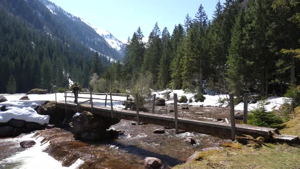 Still shot of a young man walking over a wooden bridge on a hiking route in the Swiss alps over a ca