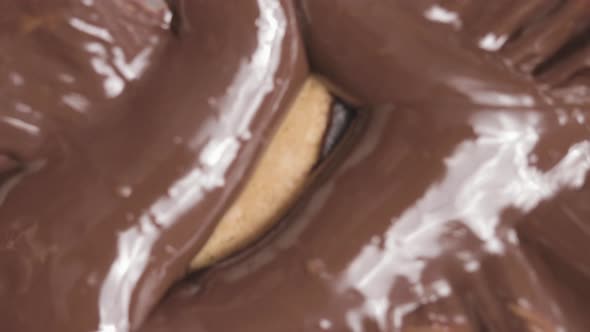 Chocolate chip cookie reveal from liquid brown chocolate, close up view