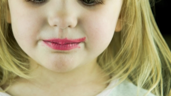 The Little Cute Girl Makes Up Lips With Red alt