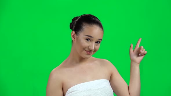 Young Woman Pointing Finger To Side on Green Screen at Studio. Slow Motion