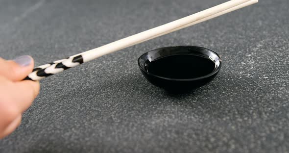 Chopsticks and soy sauce on black stone slate