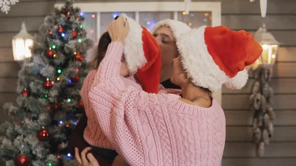 Happy Family in Pullovers Hat Hugging at Christmas Porch