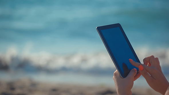 Woman Use On Beach By The Sea With Touch Pad 