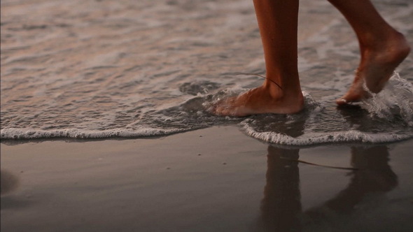 Young Girl Walking on the Beach at Evening Time