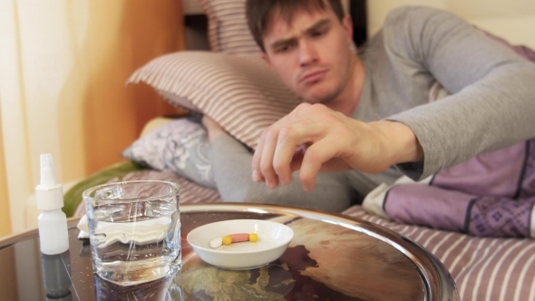 Sick Man Taking Pill While Lying On Bed. 