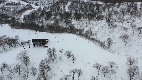 people skiing past a chair lift on a snow slope in nozwa onsen ski resort in nagano japan, aerial