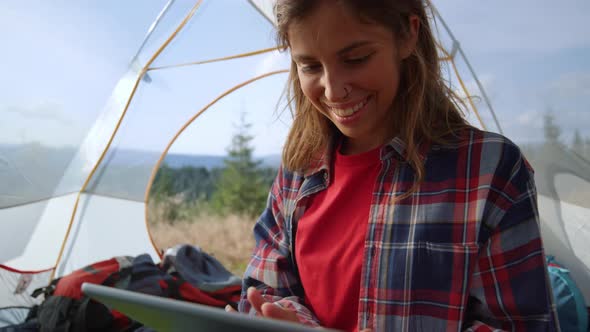 Girl Shopping Online on Digital Tablet in Tent with Mountains on Background